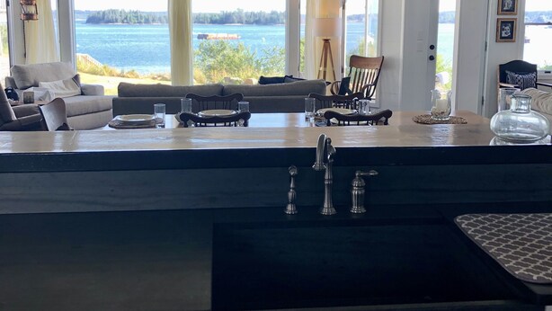 Une cuisine moderne dotée d’un grand îlot central, d’un coin repas offrant une vue sur l’eau et d’un espace salon confortable avec vue.