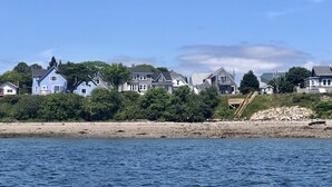 Une zone résidentielle côtière, avec des maisons le long du littoral, un ciel dégagé et une eau calme.