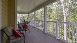 A covered porch with wooden flooring, white railings, and outdoor furniture.