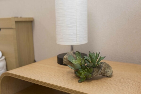 A wooden table with a small succulent plant on a rock, a black lamp, and a wooden chair in the background.