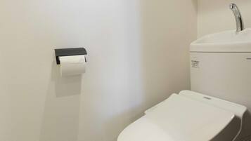 A modern bathroom with a toilet, sink, and toilet paper holder.