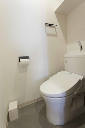 A modern bathroom with a toilet, sink, and toilet paper holder. - Pal Terrace Fujimi (Urayasu)