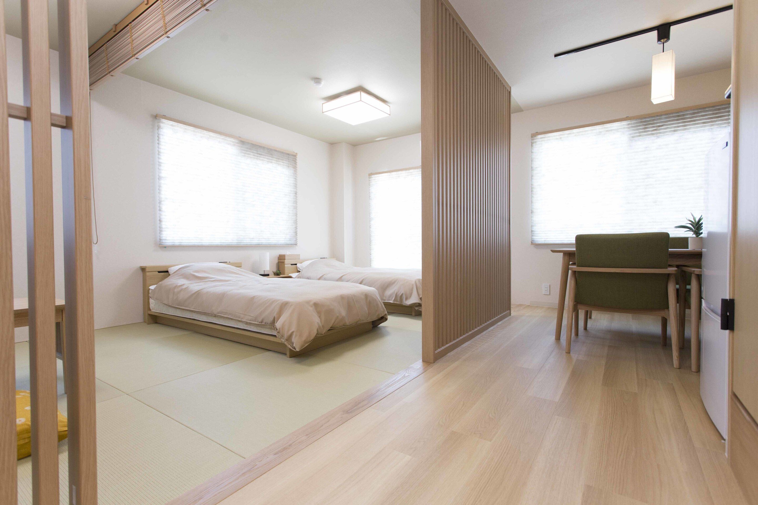 A modern bedroom with two beds, a desk, and a chair.