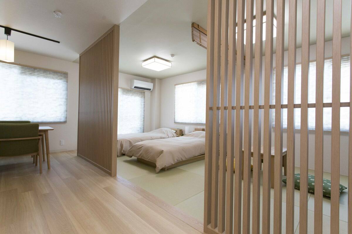 A modern hotel room with a wooden floor, a bed, a desk, and a chair.