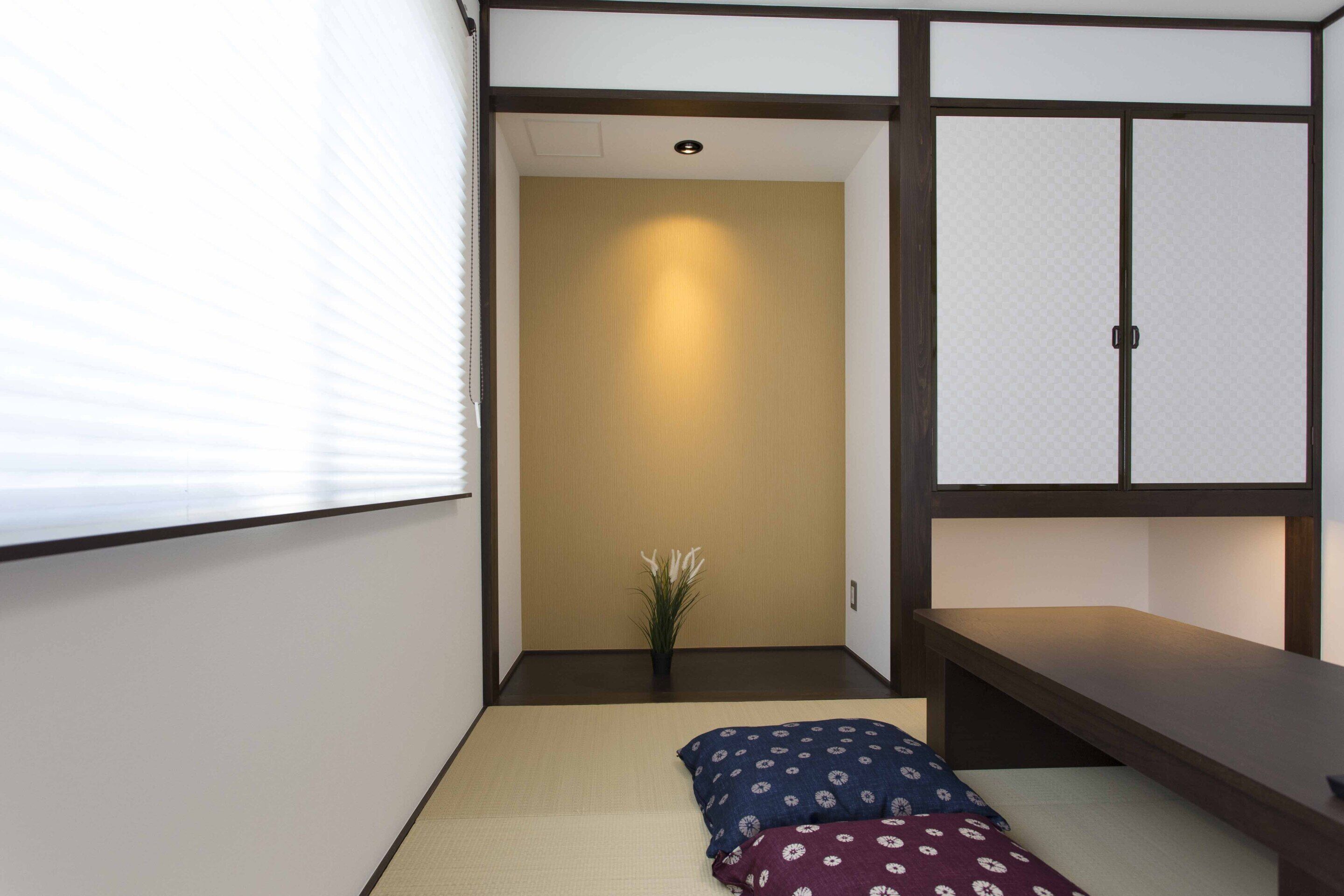 A traditional Japanese-style room with tatami flooring, a low wooden bed, a small table, and a sliding door.