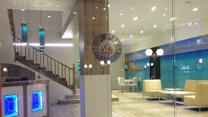 Un moderno vestíbulo de hotel con mostrador de recepción, área de estar y una escalera.