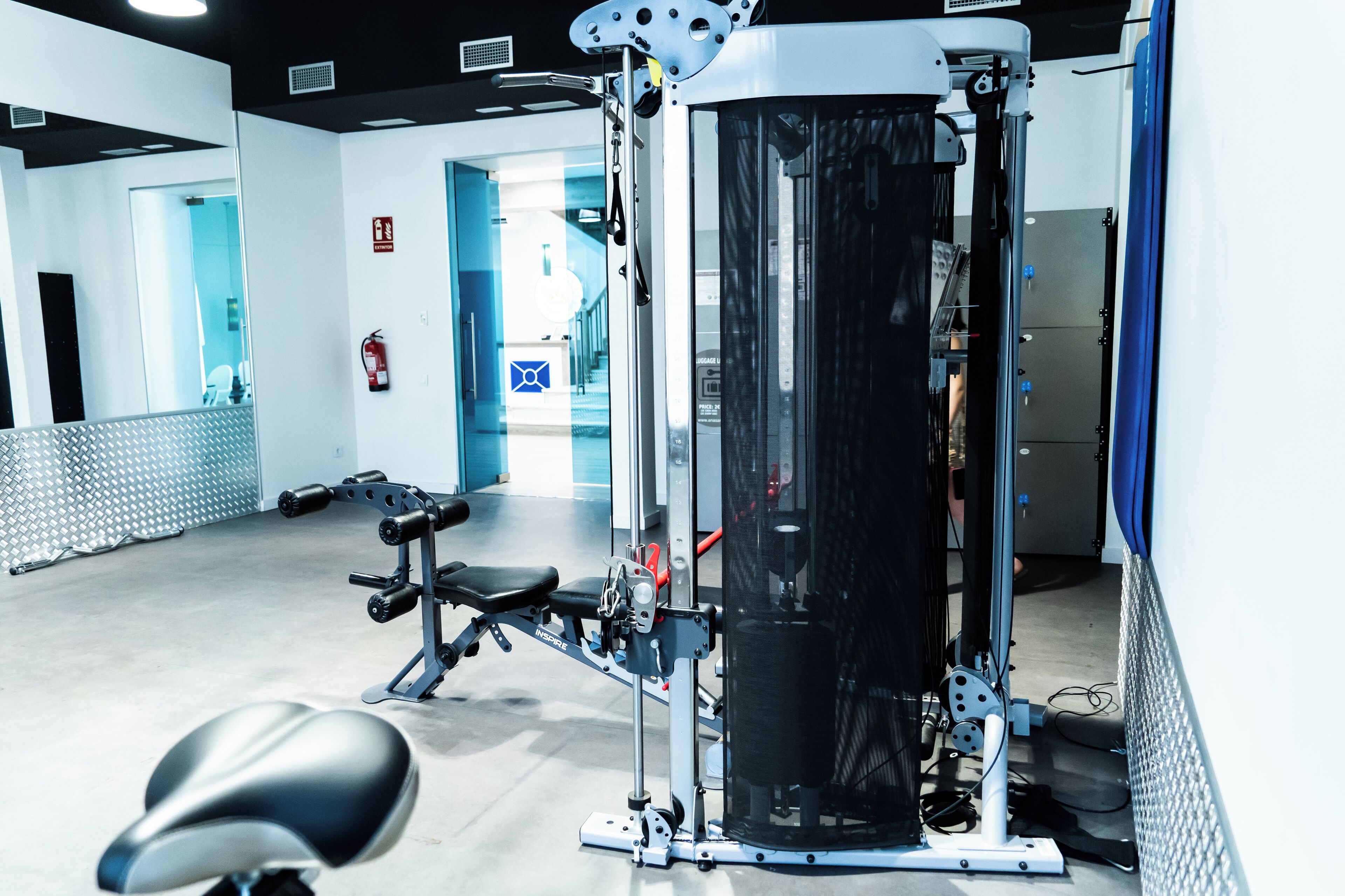 A gym with exercise equipment, a bench, and a mirrored wall.