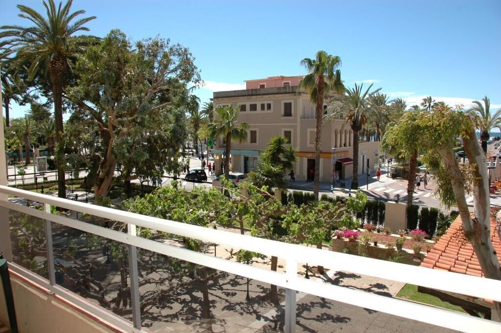 Un balcón con vista a una calle bordeada de palmeras y edificios.