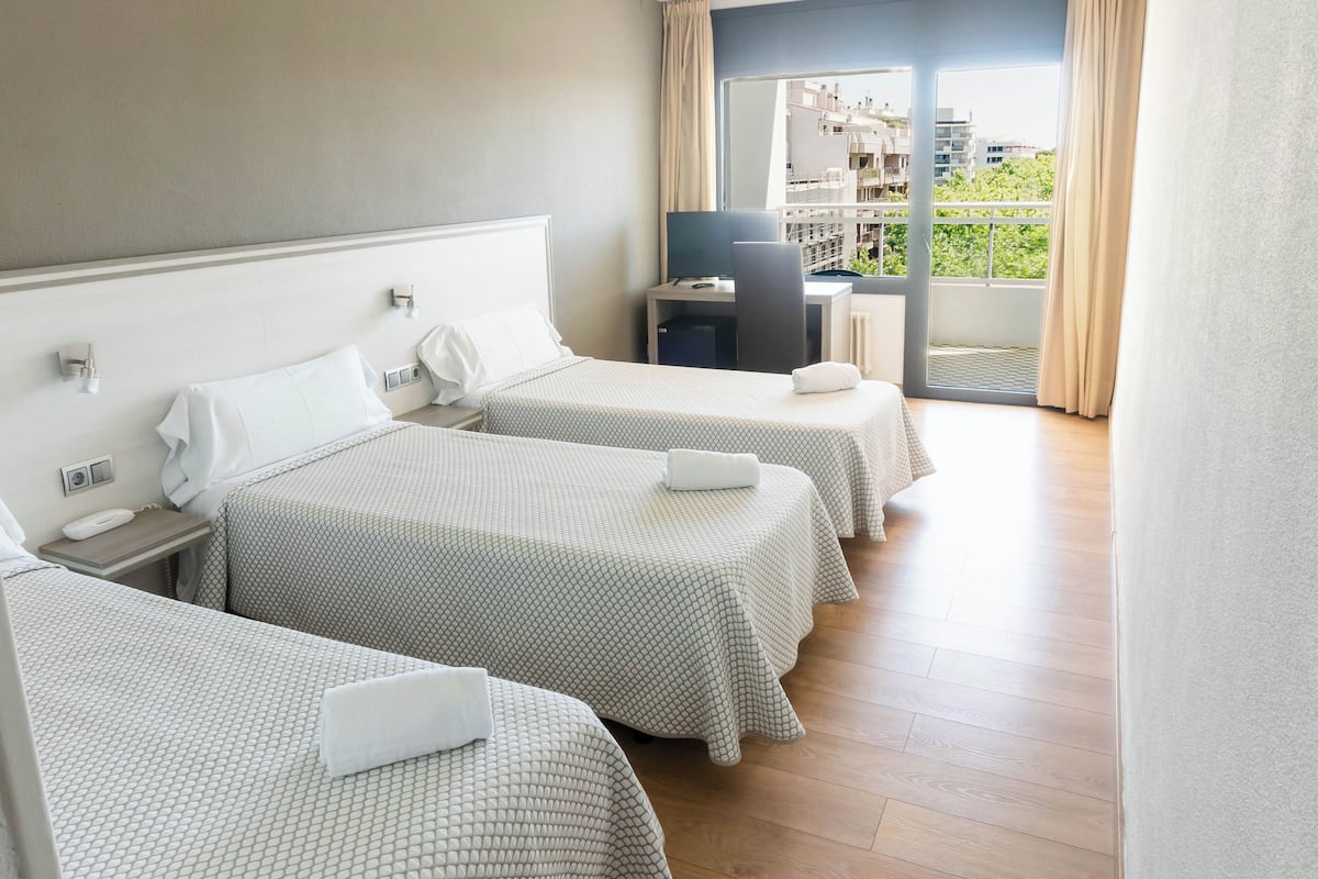 Habitación de hotel con dos camas, un escritorio y vistas a la ciudad.