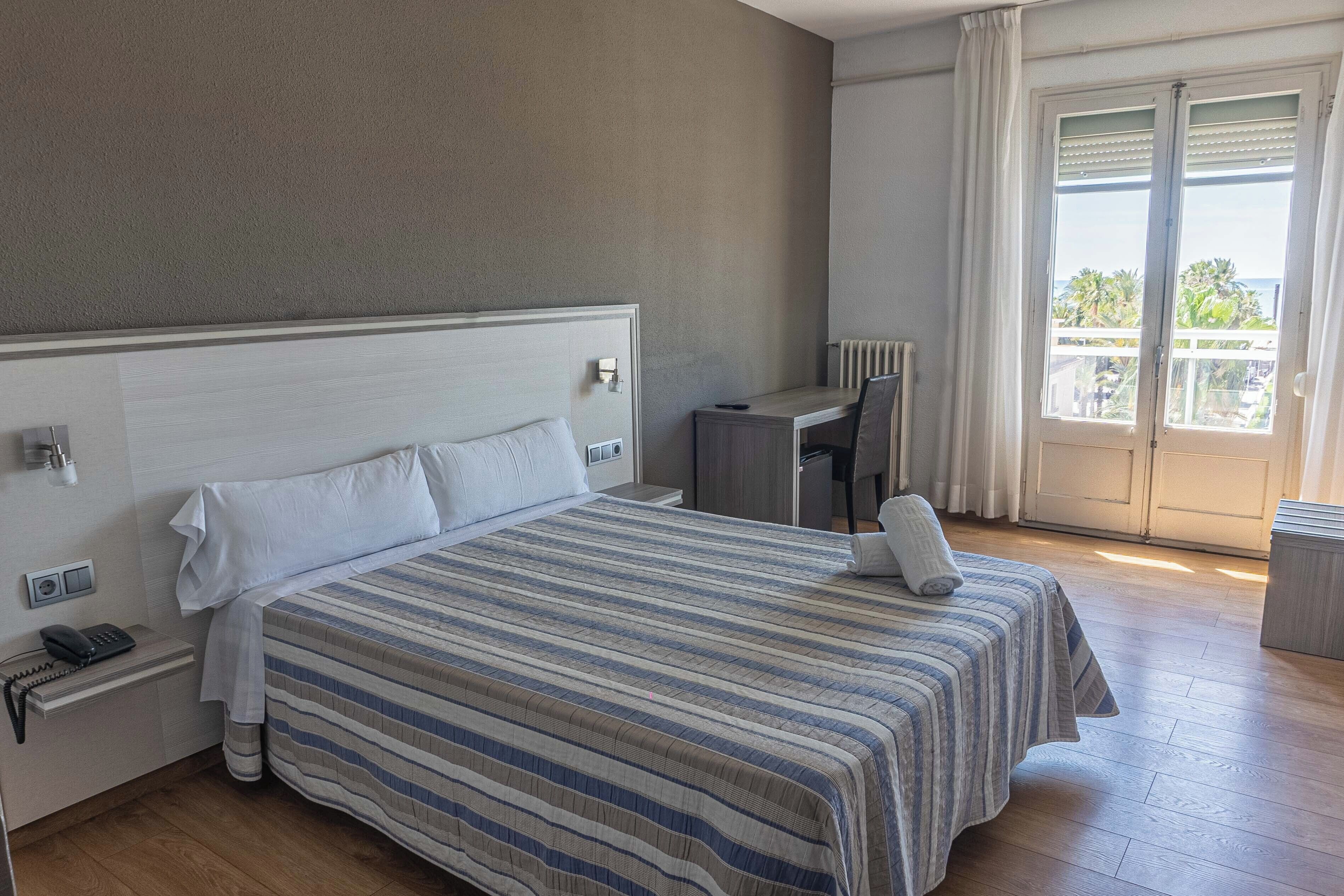 Habitación de hotel con cama, escritorio y vista al exterior.