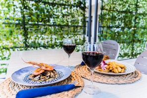 A table set with seafood, wine glasses, and plates on a woven placemat. - Hotel Planas (Salou)