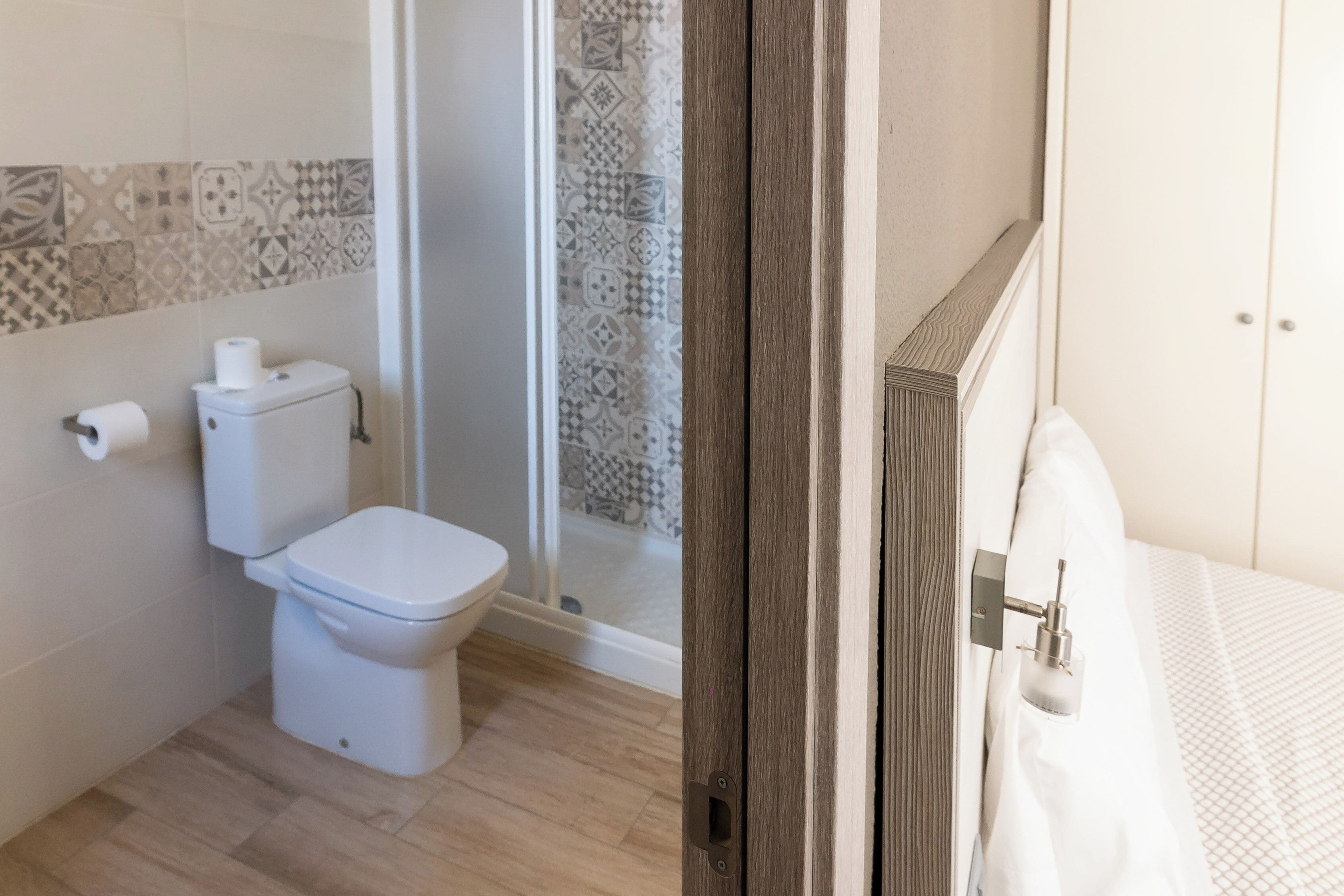 A bathroom with a toilet, shower, and a wooden door.