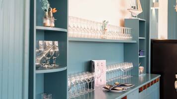 A bar area with shelves of wine glasses and a counter with plates and cutlery.