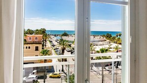 Vista desde una ventana que da a una playa, un estacionamiento y una carretera con coches.