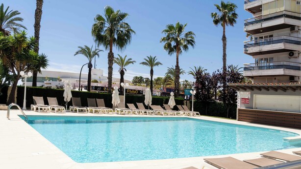 Una piscina con tumbonas y palmeras.