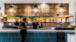 Zona de bar con pared de madera decorada, luces colgantes y un menú en pizarra.