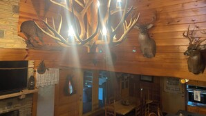A wooden interior with a chandelier made of antlers, mounted deer heads, and a stone wall. - Lake View Lodge - Beautiful Year Round View of Center Hill Lake and Marina (Lancaster)