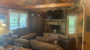A cozy cabin interior with a stone fireplace, wooden furniture, and a ceiling with wooden beams. - Lake View Lodge - Beautiful Year Round View of Center Hill Lake and Marina (Lancaster)