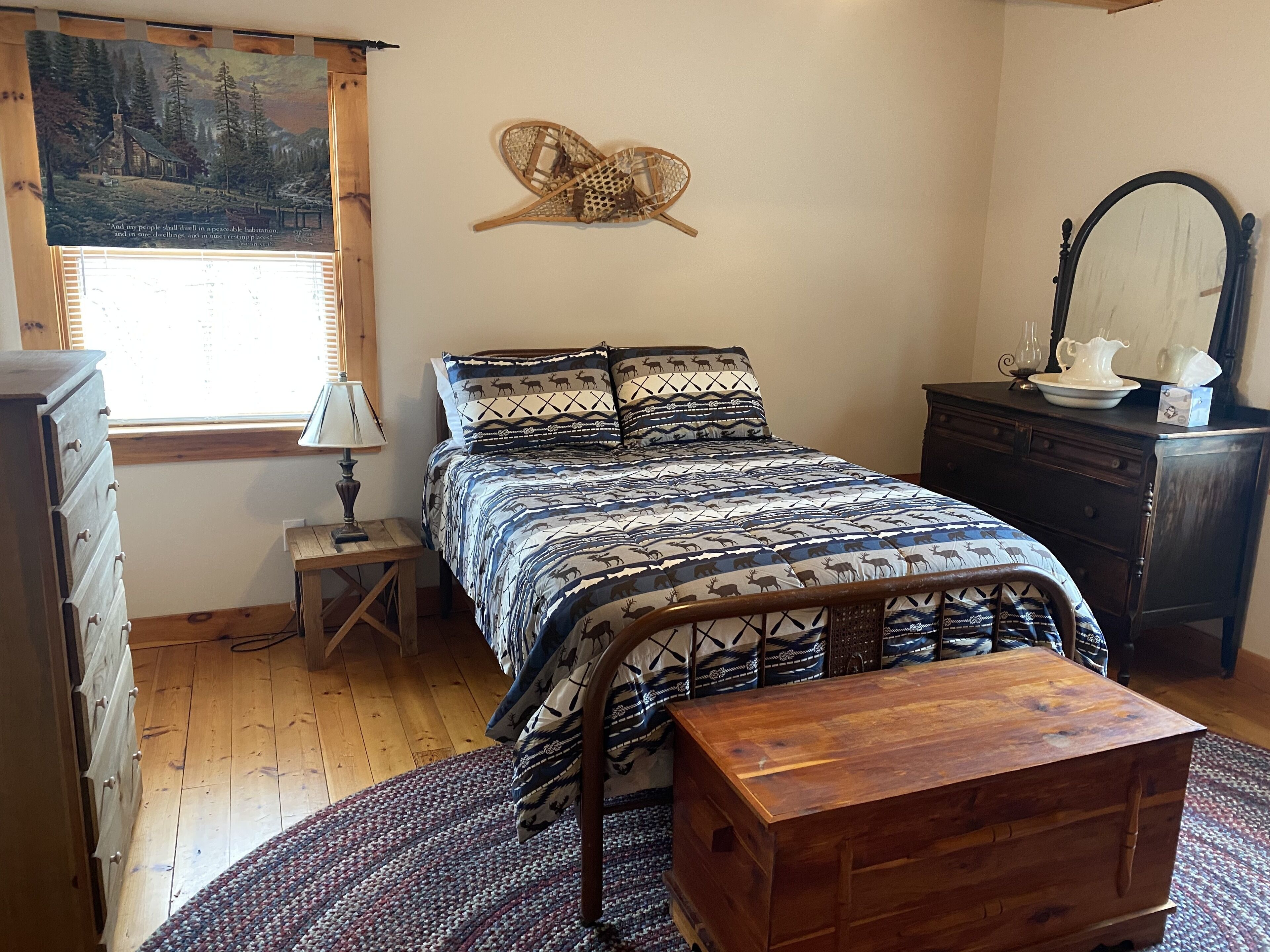 A bedroom with a bed, dresser, nightstand, and a wooden chest.