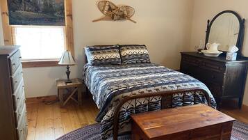 A bedroom with a bed, dresser, nightstand, and a wooden chest.