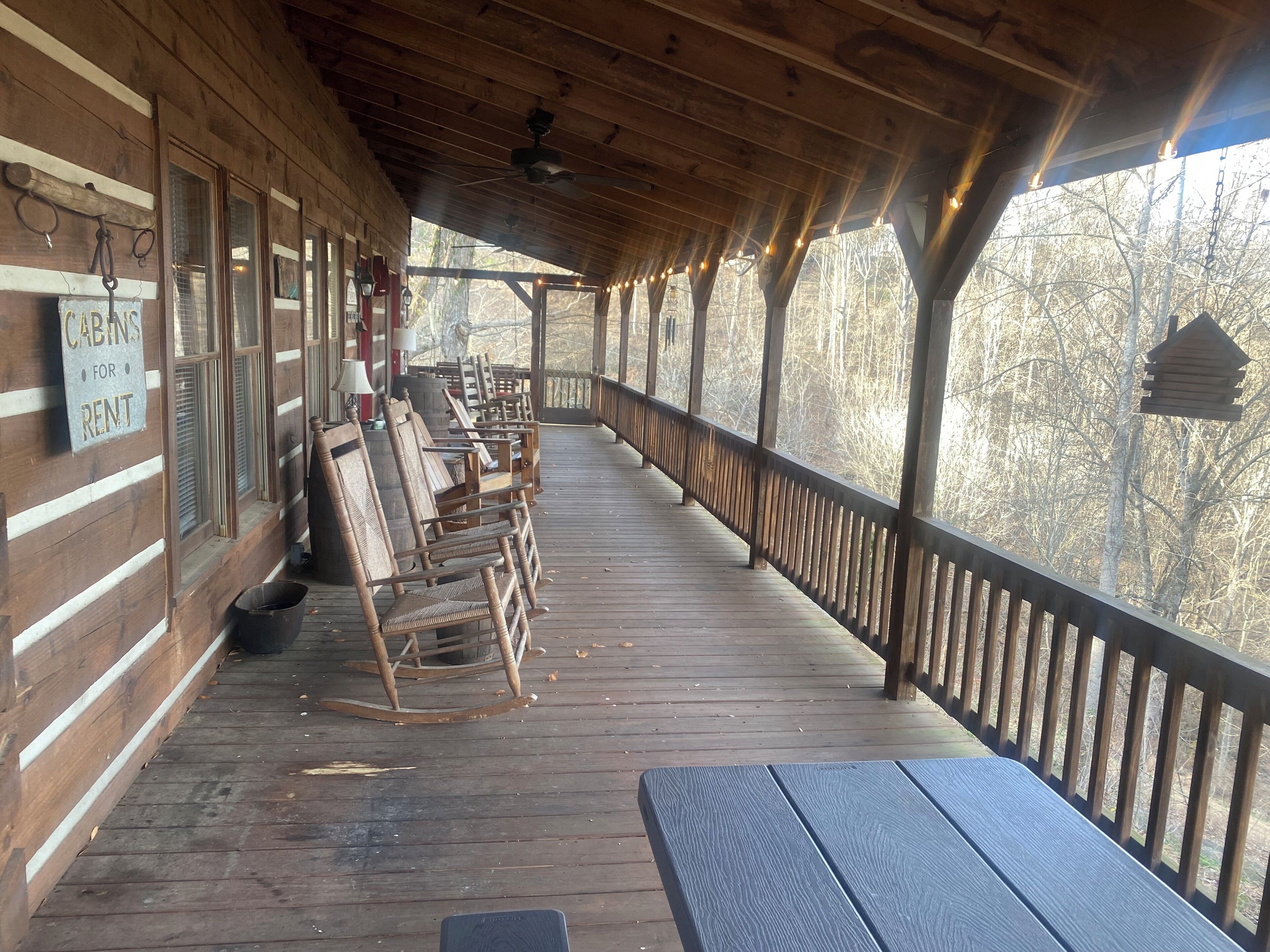 A covered porch with wooden benches and a sign indicating cabins for rent.