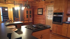 A wooden cabin-style kitchen with a central island stove, wooden cabinets, and a built-in oven. - Lake View Lodge - Beautiful Year Round View of Center Hill Lake and Marina (Lancaster)