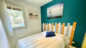 Un dormitorio con una cama, una ventana y una pared color aguamarina.