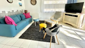 Una sala de estar con un sofá, una mesa de centro, un televisor y una silla.