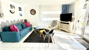 Una sala de estar con sofá, una mesa de centro, televisor y una silla.