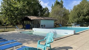 Zona de piscina con sillones reclinables, un edificio pequeño y cielo despejado.