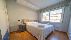 A bedroom with a bed, bedside table, and a window with blinds.
