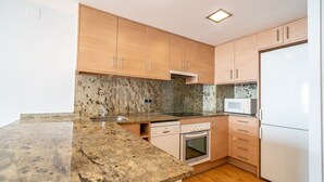 A kitchen with granite countertops, wooden cabinets, a microwave, a dishwasher, and an oven.