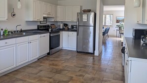 A modern kitchen with white cabinets, stainless steel appliances, and a herringbone-patterned floor.