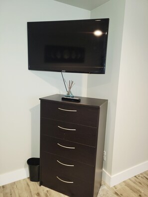 A dark wooden cabinet with drawers, a small vase with reeds, and a flat-screen TV mounted above it.