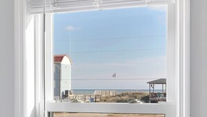 Ein Fenster mit Blick auf einen Strand, ein Gebäude und einen Zaun.