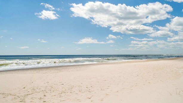 Ein Strand mit blauem Himmel und Wellen im Meer.