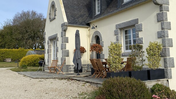 A house with a stone facade, multiple windows, and a patio area with outdoor furniture. - Country by the sea! (Tréflaouénan)