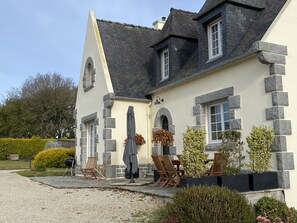 A house with a stone facade, multiple windows, and a patio area with outdoor furniture.