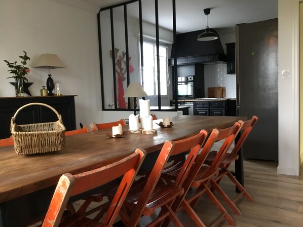Ein Essbereich mit einem Holztisch, orangefarbenen Stühlen und einem Korbwäschesessel.