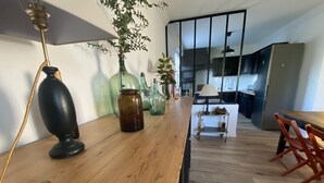 A kitchen with a wooden countertop, a vase, and a lamp. There is a dining area with a table and chairs. - Country by the sea! (Tréflaouénan)