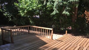 A wooden deck with a railing, surrounded by trees.