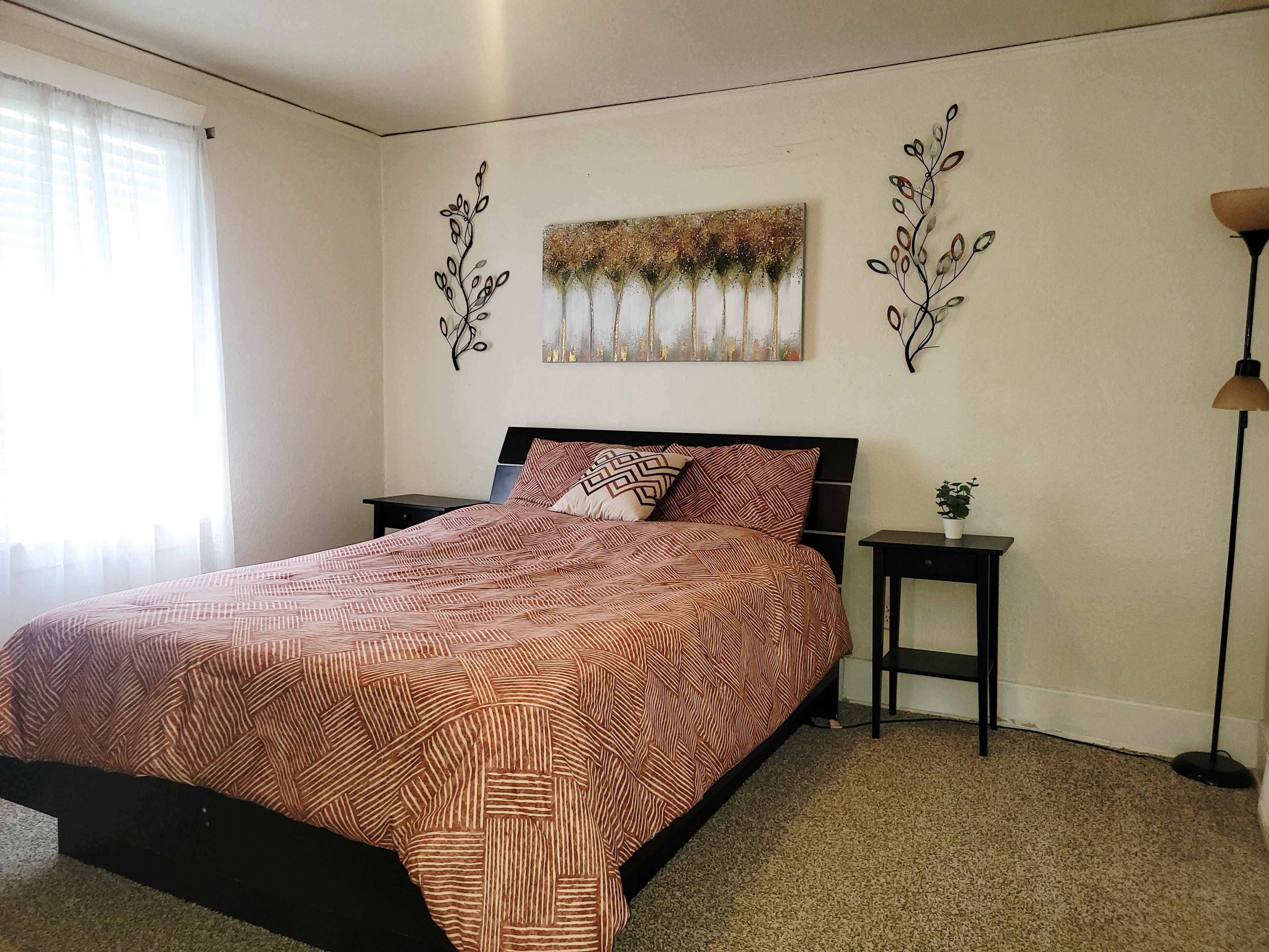 A bedroom with a bed, nightstands, a lamp, and wall art.