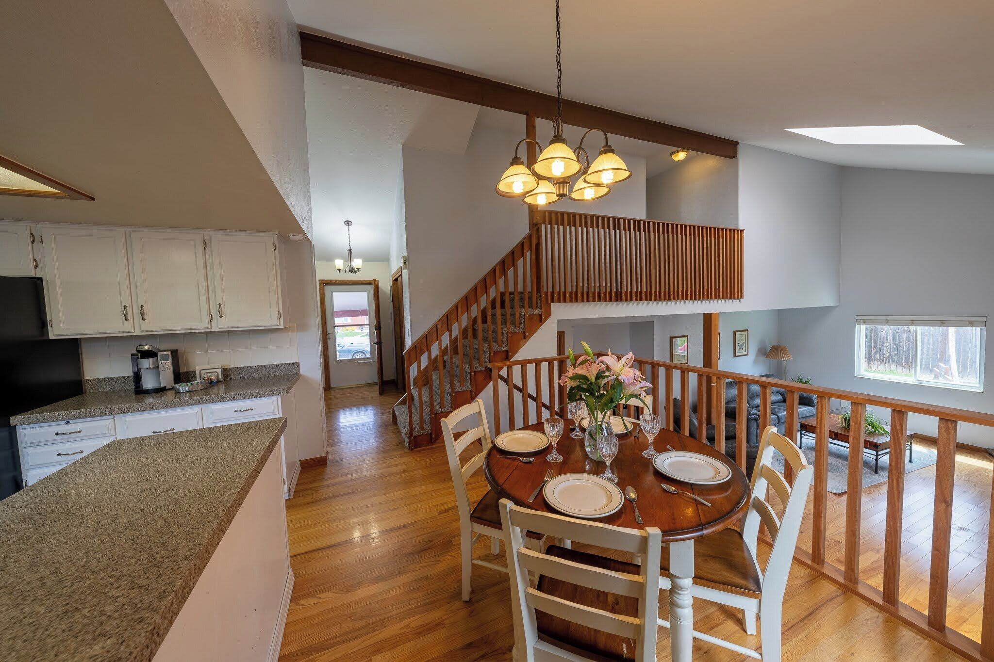 A spacious kitchen with wooden cabinets, a granite countertop, and a dining area with a wooden table set for four.