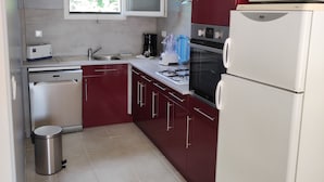 Eine moderne Küche mit Edelstahlgeräten, einem Fenster und einem roten Schrank.