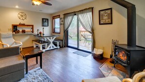 A cozy living room with a fireplace, a ceiling fan, and a dining area with a table and chairs.