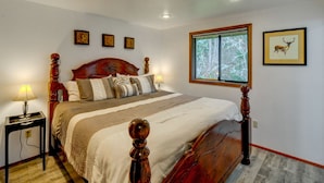 A neatly arranged bedroom with a wooden bed, bedside lamps, and a framed deer picture on the wall.