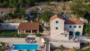 Un edificio de piedra con piscina, zona de estar al aire libre y vistas del paisaje circundante.