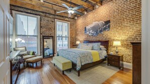A bedroom with a large bed, a wooden bench, a dresser, and a mirror. - MtnMusicLoft,Find Your Rhythm in Heart of Downtown (Bristol)
