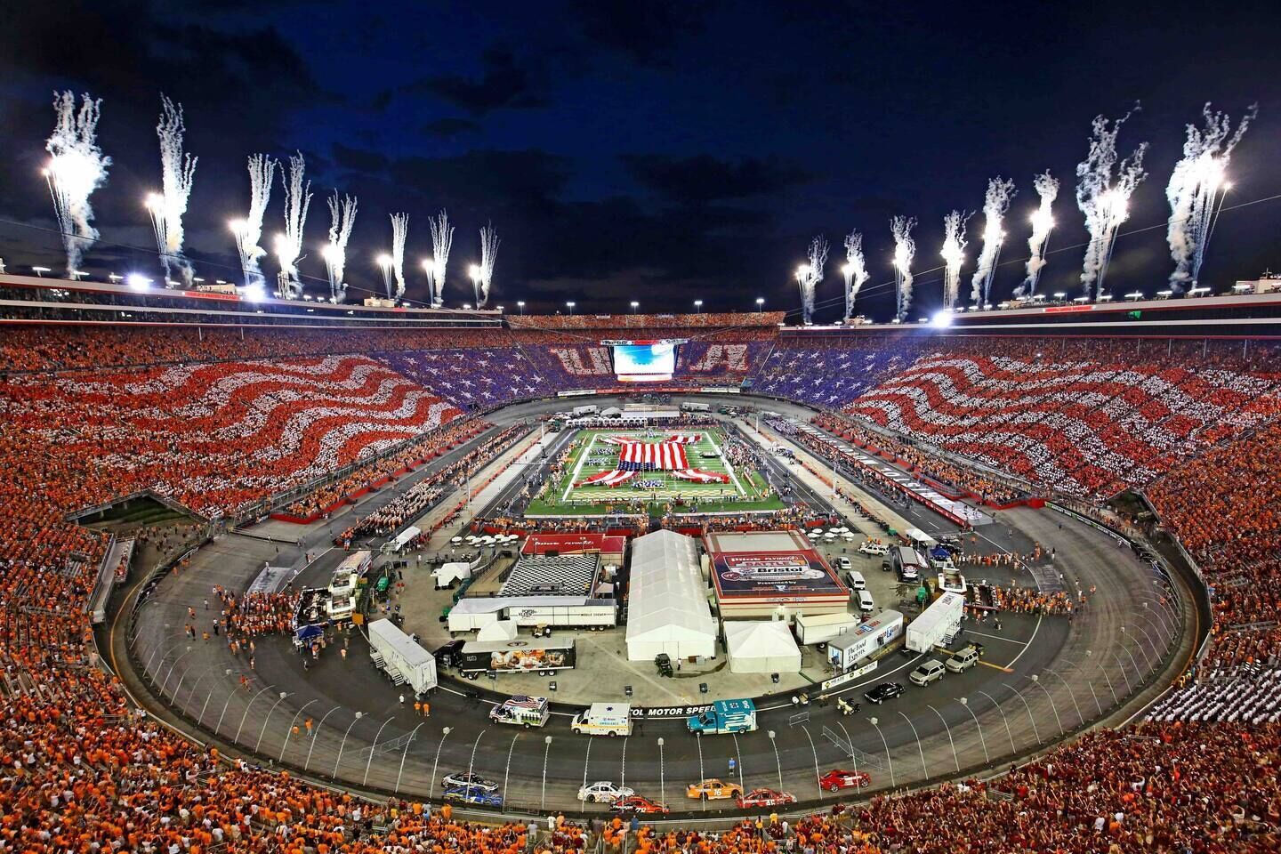 A large stadium with a central field, surrounded by a crowd of spectators.