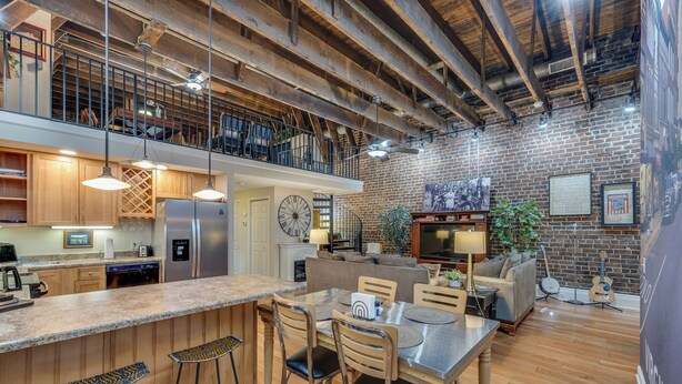 A spacious kitchen with a large island, wooden bar stools, and a dining area with a table and chairs. - MtnMusicLoft,Find Your Rhythm in Heart of Downtown (Bristol)